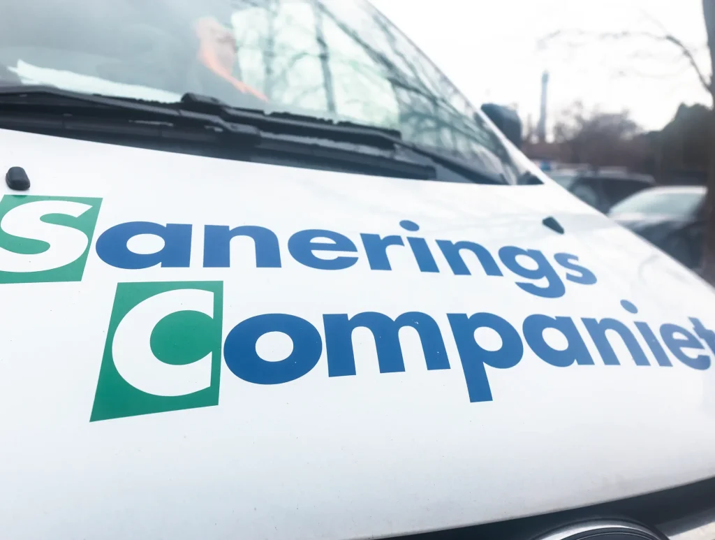 Sanerings Companiets logotyp på ett vitt fordon.