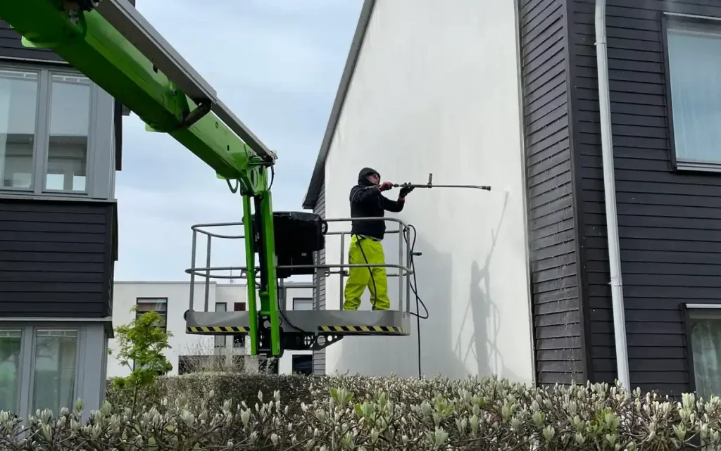 fasadtvätt på gaveln av ett vitputsat lägenhetshus